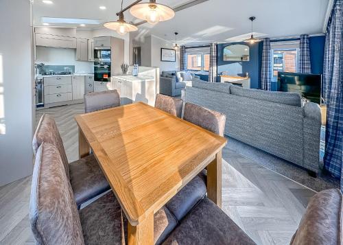 a dining room with a wooden table and couches at Watermill Leisure Park in Moortown