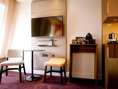 a room with a table and two chairs and a mirror at Mercure Lyon Centre Plaza République in Lyon