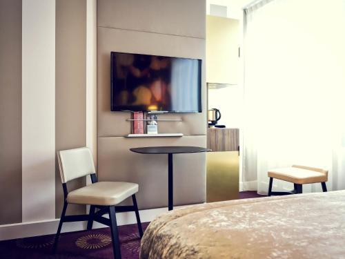 a hotel room with a bed and a table and chairs at Mercure Lyon Centre Plaza République in Lyon