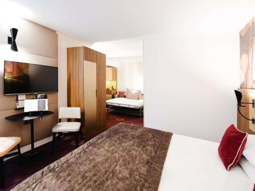 a hotel room with a large bed and a desk at Mercure Lyon Centre Plaza République in Lyon