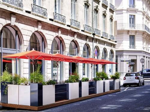 a building with red umbrellas on a city street at Mercure Lyon Centre Plaza République in Lyon