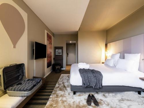 a hotel room with a large bed and a couch at Mercure Grenoble Meylan in Meylan