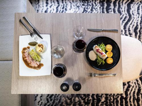 a table with two plates of food and glasses of wine at Mercure Grenoble Meylan in Meylan