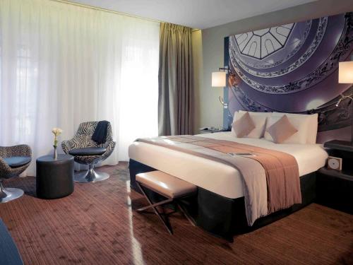 a hotel room with a large bed and a chair at Mercure Lyon Centre Beaux-Arts in Lyon