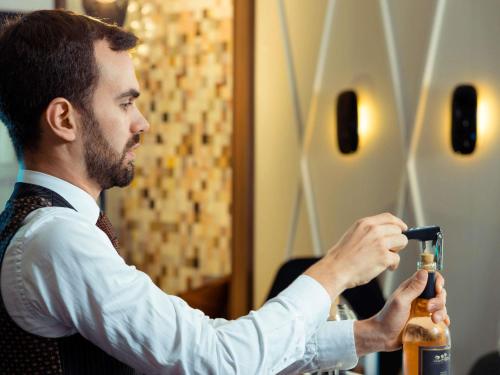 a man in a tie is holding a bottle at Mercure Lyon Centre Beaux-Arts in Lyon