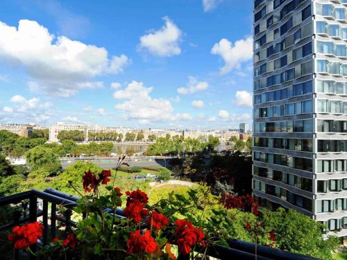 a balcony with red flowers and a tall building at Mercure Paris Tour Eiffel Pont Mirabeau in Paris