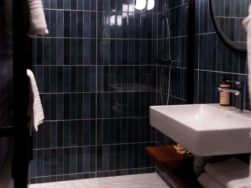 a black tiled bathroom with a sink and a mirror at Mercure Paris Tour Eiffel Pont Mirabeau in Paris