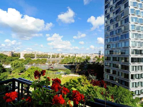 a balcony with red flowers and a tall building at Mercure Paris Tour Eiffel Pont Mirabeau in Paris