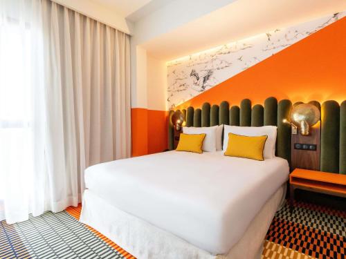 a bedroom with a large white bed with yellow pillows at Mercure Shéhérazade Rabat in Rabat