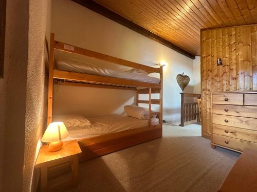 ein Schlafzimmer mit Etagenbetten mit einer Lampe und einer Kommode in der Unterkunft Duplex confortable avec balcon au cœur de Morillon Village - FR-1-642-39 in Morillon