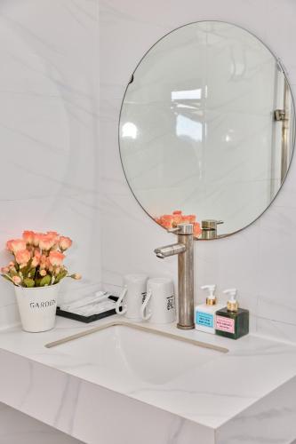 a bathroom sink with a mirror and flowers on it at Phoenix Flower Hotel & Travel in Cat Ba