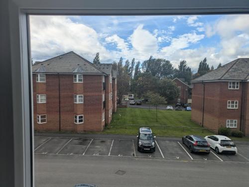 a view from a window of a parking lot with cars at Comfortable and Peaceful 2 Bedroom Flat with Shared Bathroom and Kitchen Close to Manchester Airport in Manchester