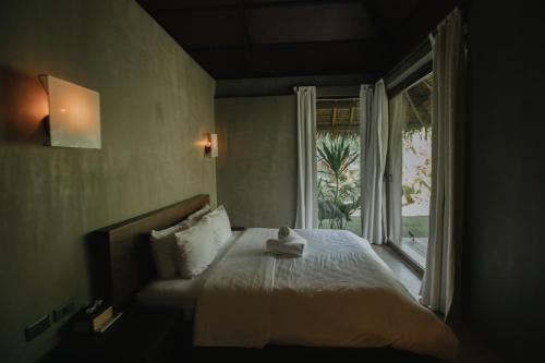 a bedroom with a bed and a large window at Mémé Villa Siargao in General Luna