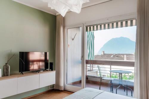 a bedroom with a bed and a tv and a window at Vinorum Studio by Quokka 360 - Cozy and sunny with balcony in Massagno