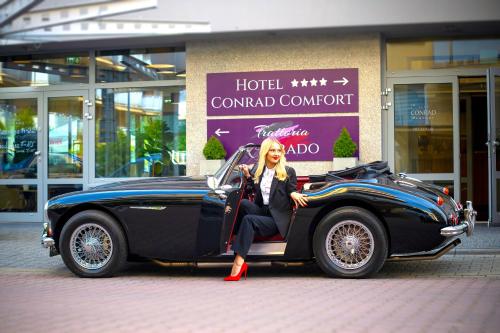 a man sitting in a car in front of a hotel condominium at Hotel CONRAD Comfort in Kraków