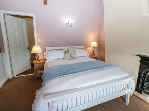 een slaapkamer met een groot wit bed met twee lampen bij Ewe Cottage in Masham