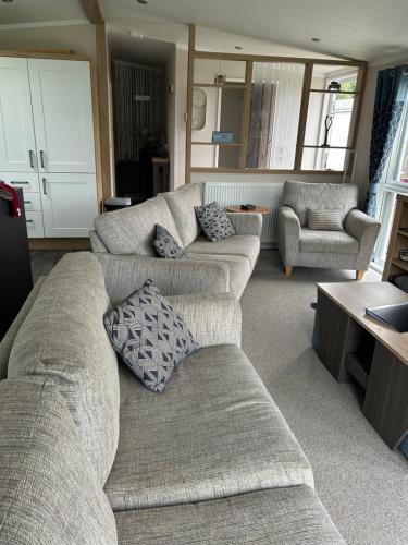 a living room with two couches and a table at Blissful Lodge Haven Lakeland in Flookburgh