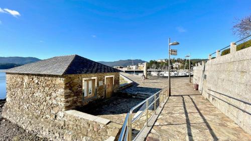 a stone building next to a wall next to the water at The Cliffs - Ortigueira Kalmak in Santa Marta de Ortigueira