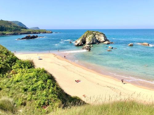 a beach with people swimming in the ocean at The Cliffs - Ortigueira Kalmak in Santa Marta de Ortigueira