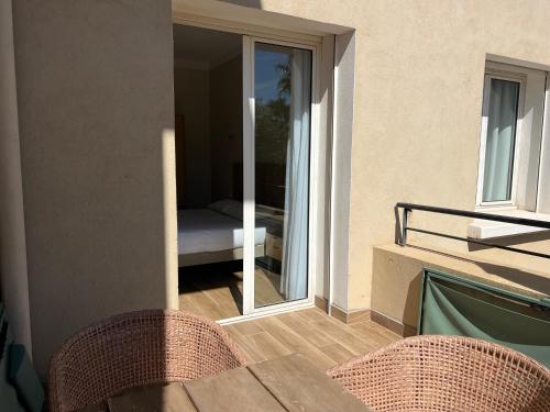 a balcony with a table and chairs and a bedroom at Adonis Sanary Grand Hôtel des Bains in Sanary-sur-Mer