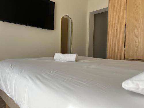 a bedroom with a white bed with a flat screen tv at Adonis Sanary Grand Hôtel des Bains in Sanary-sur-Mer