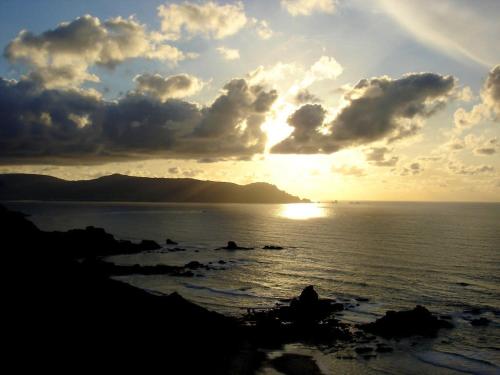a sunset over the ocean with the sun setting at The Cliffs - The Painted Mill in O Barqueiro