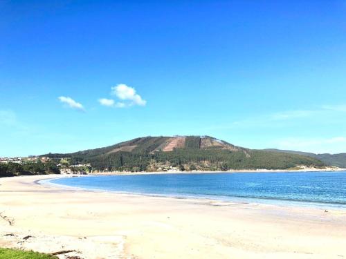 a view of a beach with a hill in the background at The Cliffs - The Painted Mill in O Barqueiro