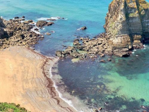 an aerial view of a beach with rocks and the ocean at The Cliffs - The Painted Mill in O Barqueiro