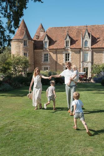 a family playing in a yard in front of a house at Domaine des Etangs, Auberge Collection in Massignac