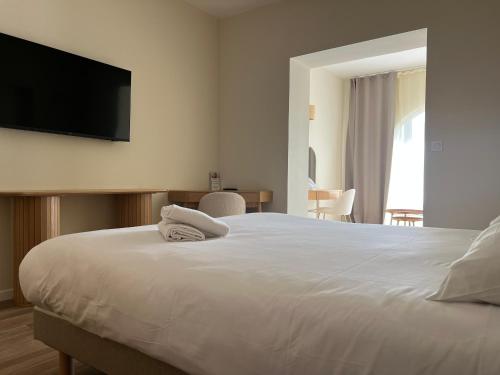 a bedroom with a white bed with a flat screen tv on the wall at Adonis Sanary Grand Hôtel des Bains in Sanary-sur-Mer