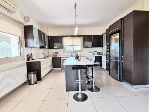 a kitchen with black cabinets and a white tile floor at Orchard Blossom Private Villa With Pool in Phrenaros