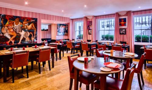 a restaurant with tables and chairs and a painting on the wall at The Pelham London - Starhotels Collezione in London