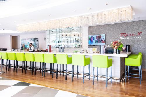 a bar with neon green bar stools in a restaurant at Holiday Inn Mauritius Mon Trésor by IHG in Blue Bay