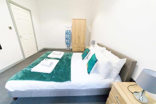 a bedroom with a large bed with a green blanket at Cosy Central Blackburn Apartment in Blackburn