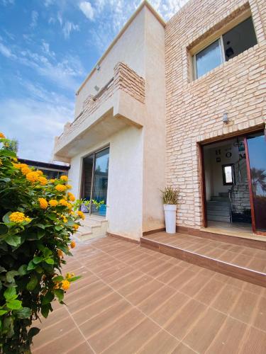 a house with a patio with flowers in front of it at Villa Sunset Moulay Bouzerktoun in Essaouira