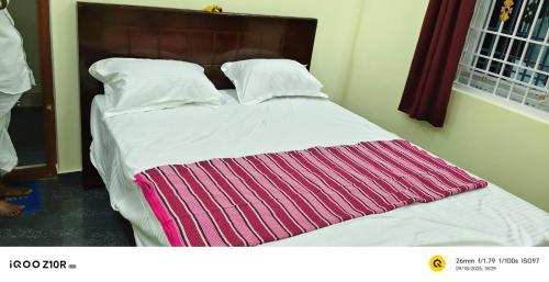 a bed with a striped blanket on top of it at S M LODGe in Dharmapuri