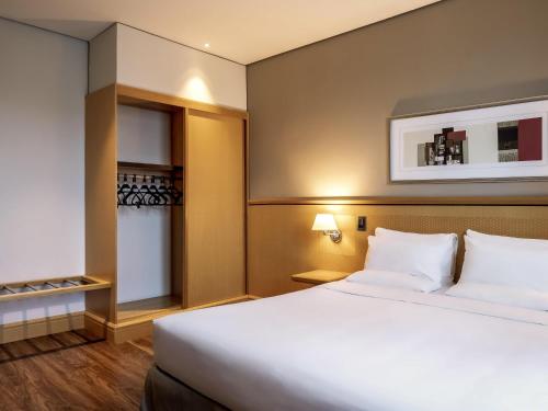 a bedroom with a large white bed and a closet at Novotel Sao Paulo Center Norte in Sao Paulo