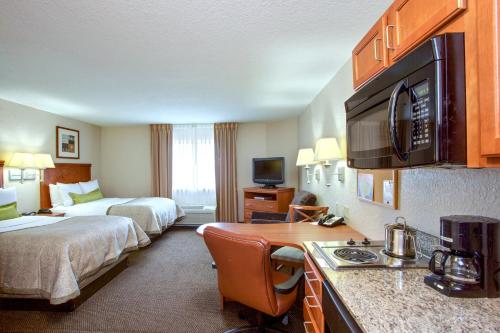 a hotel room with two beds and a kitchen with a desk at Candlewood Suites Chesapeake-Suffolk by IHG in Chesapeake