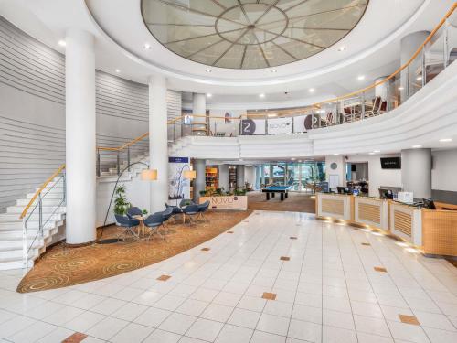 a large lobby with a piano in the center at Novotel Szeged in Szeged