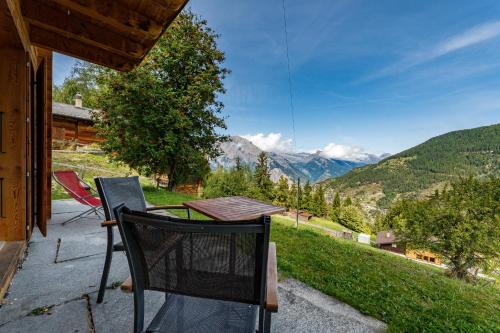a table and chairs on a porch with a view of mountains at Chalet Colonia in La Tzoumaz