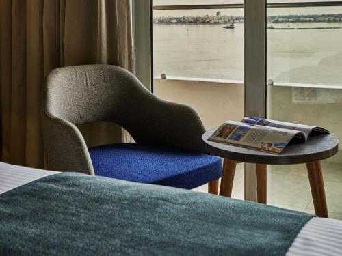a room with a chair and a book on a table at Mercure Ismailia Forsan Island in Ismailia