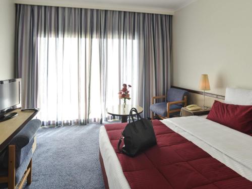a hotel room with a bed with a bag on it at Mercure Ismailia Forsan Island in Ismailia