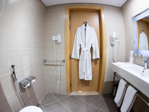 a bathroom with a robe hanging on a shower door at Mercure Ismailia Forsan Island in Ismailia