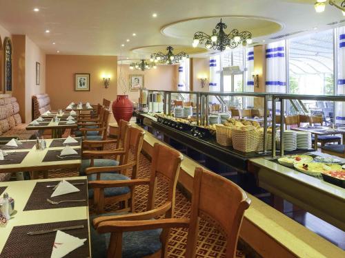 a restaurant with tables and chairs and a buffet at Mercure Ismailia Forsan Island in Ismailia