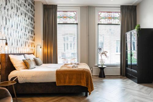 a bedroom with a large bed and two windows at City Center Poppodium 013 Stadsvilla Tilburg in Tilburg