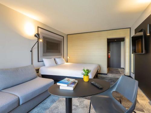 a hotel room with a bed and a couch and a table at ibis Strasbourg Centre Gare in Strasbourg