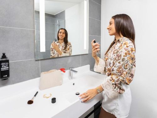 a woman taking a picture of herself in a bathroom mirror at ibis Strasbourg Centre Gare in Strasbourg