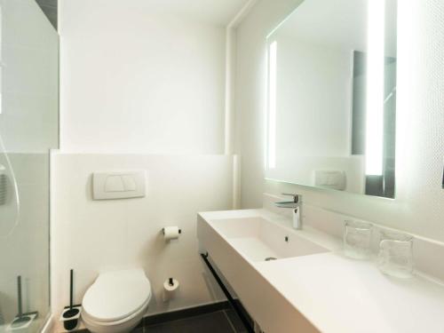 a white bathroom with a toilet and a sink at ibis Strasbourg Centre Gare in Strasbourg