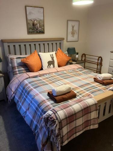 a bedroom with a large bed with a plaid blanket at Struan Cottage in Ballater