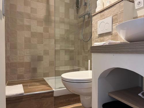 a bathroom with a shower and a toilet and a sink at Adonis Sanary Grand Hôtel des Bains in Sanary-sur-Mer